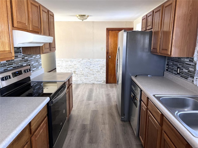 kitchen with backsplash, stainless steel appliances, wood-type flooring, and sink