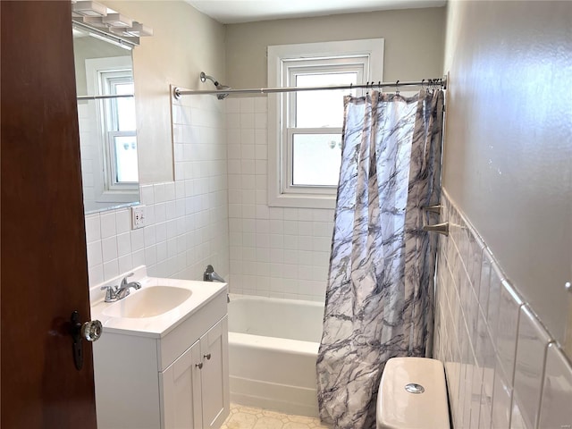 full bathroom with a healthy amount of sunlight, tile flooring, vanity, and tile walls