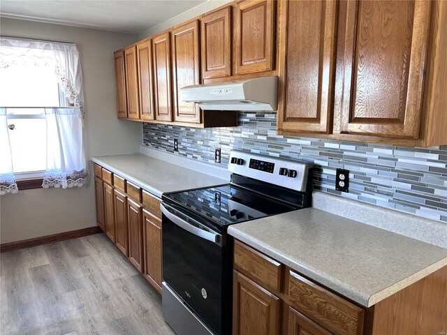 kitchen featuring custom range hood, light wood-type flooring, backsplash, and stainless steel electric range oven