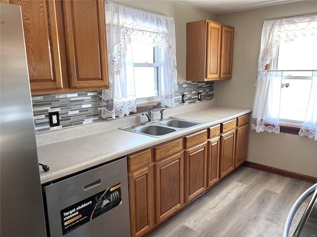 kitchen featuring tasteful backsplash, light wood-type flooring, sink, and stainless steel appliances