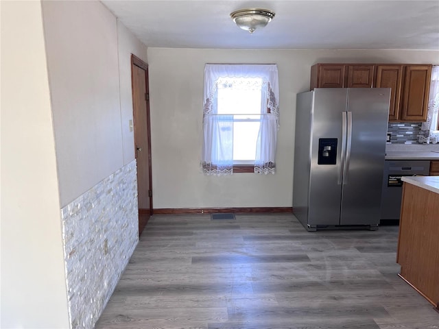 kitchen featuring backsplash, stainless steel fridge, dishwasher, and light hardwood / wood-style flooring