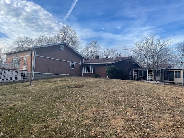 back of house featuring a lawn and a wooden deck