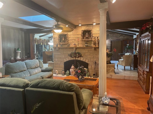 living room with decorative columns, ceiling fan, light wood-type flooring, and beamed ceiling