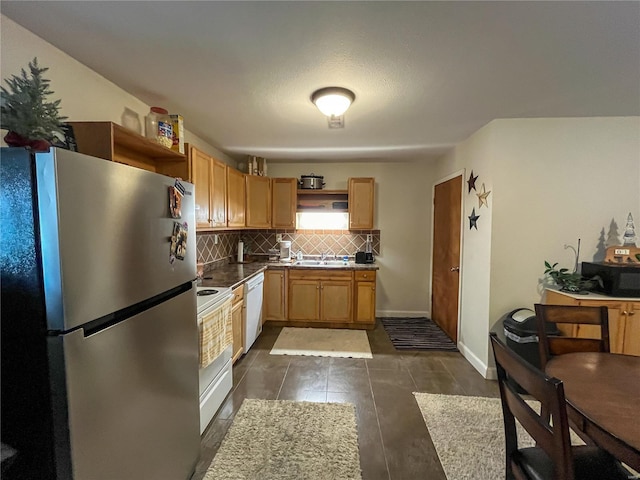 kitchen featuring tasteful backsplash, white appliances, dark tile floors, and sink