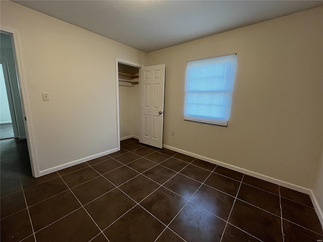 unfurnished bedroom with dark tile flooring and a closet