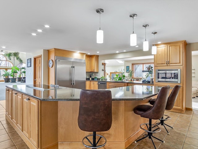 kitchen featuring a breakfast bar, built in appliances, light tile patterned floors, kitchen peninsula, and a kitchen island