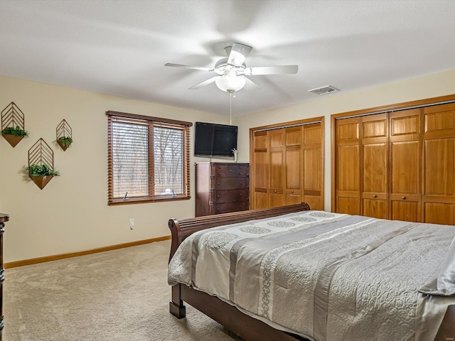 bedroom with carpet flooring, two closets, and ceiling fan