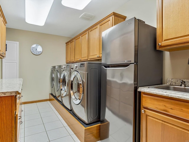 laundry room with cabinets, sink, washer and dryer, and light tile patterned floors