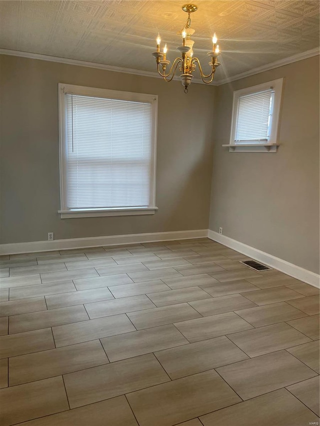 spare room featuring crown molding and a chandelier