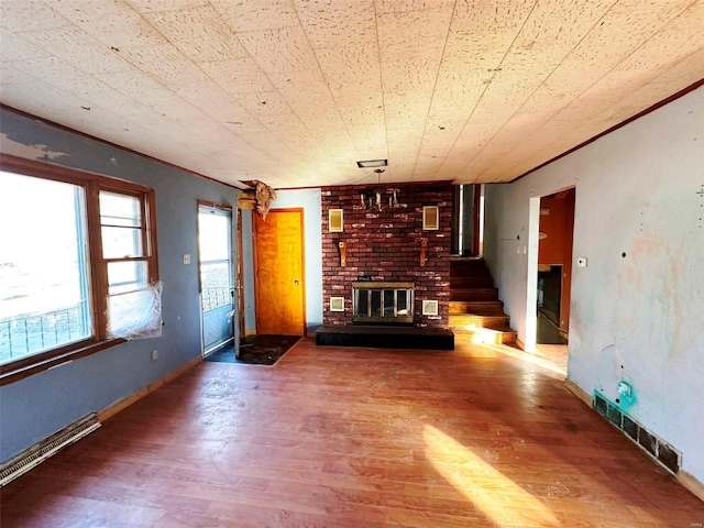 unfurnished living room with brick wall, dark hardwood / wood-style floors, crown molding, and a brick fireplace