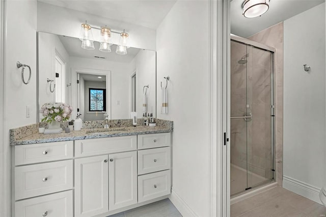 bathroom with tile floors, a shower with shower door, and vanity with extensive cabinet space