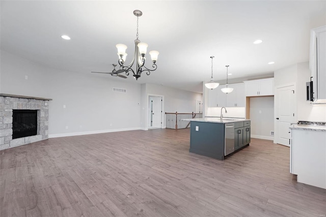 kitchen featuring decorative light fixtures, white cabinetry, a kitchen island with sink, light hardwood / wood-style floors, and a chandelier