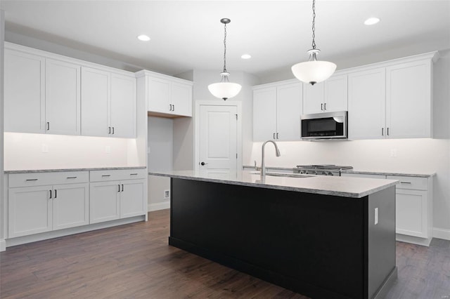 kitchen featuring dark hardwood / wood-style flooring, white cabinetry, a kitchen island with sink, backsplash, and hanging light fixtures