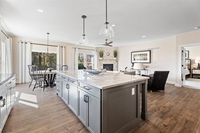 kitchen with decorative light fixtures, hardwood / wood-style floors, a kitchen island, and a fireplace