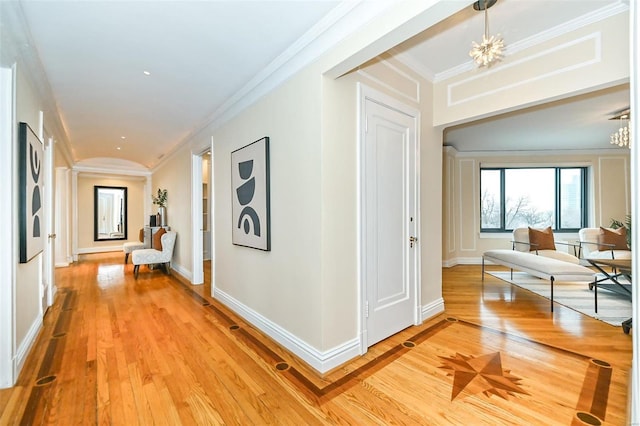 hallway featuring a chandelier, light hardwood / wood-style floors, and crown molding