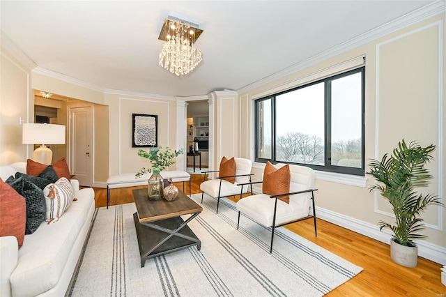 living room with ornamental molding, wood-type flooring, and a notable chandelier