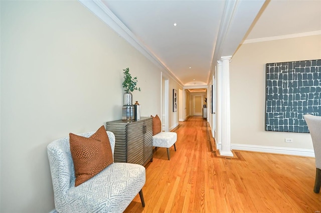 hallway with decorative columns, wood-type flooring, and ornamental molding