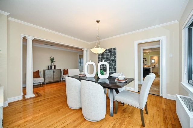 dining area featuring light hardwood / wood-style floors, ornate columns, crown molding, and radiator heating unit