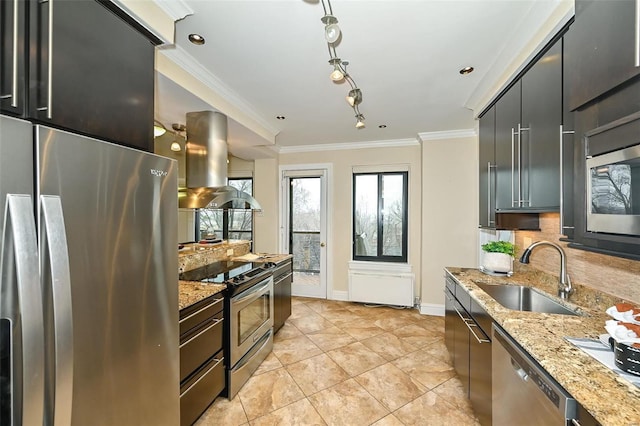 kitchen with island exhaust hood, appliances with stainless steel finishes, light stone countertops, crown molding, and sink