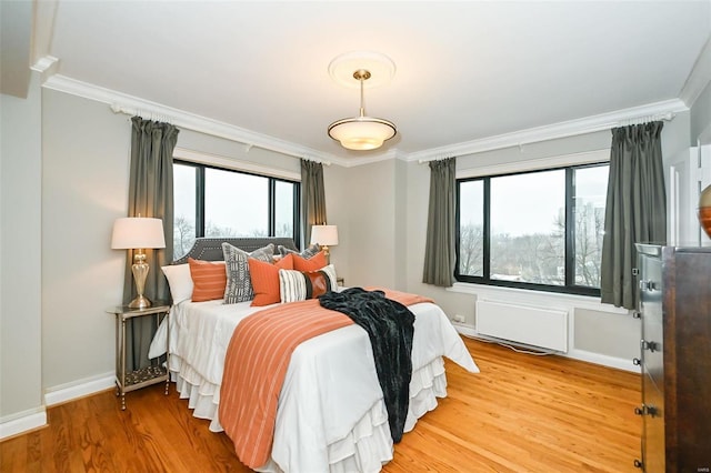 bedroom featuring hardwood / wood-style floors, crown molding, and multiple windows