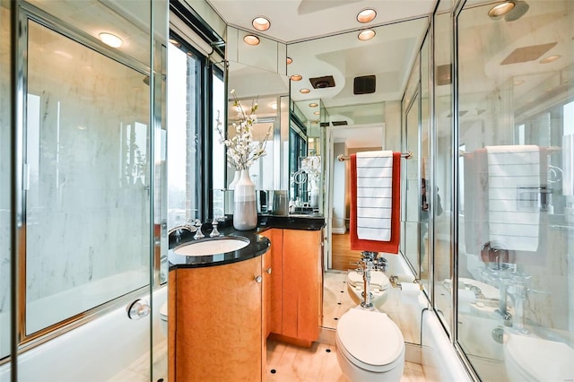 full bathroom with wood-type flooring, vanity, bath / shower combo with glass door, and toilet