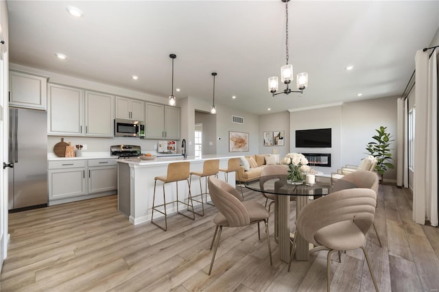 dining area featuring recessed lighting, light wood-style flooring, visible vents, and a glass covered fireplace