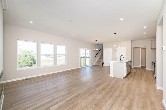 unfurnished living room featuring light wood finished floors, baseboards, stairway, and recessed lighting