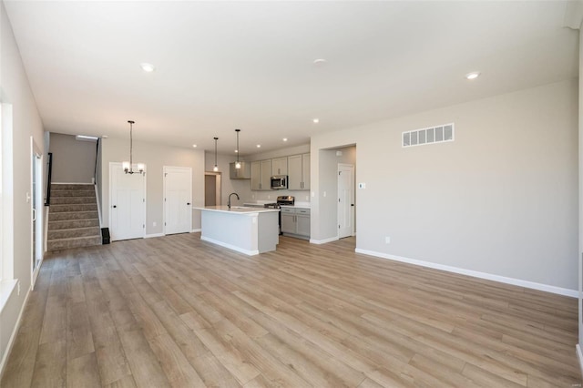 unfurnished living room with recessed lighting, a sink, visible vents, stairs, and light wood finished floors