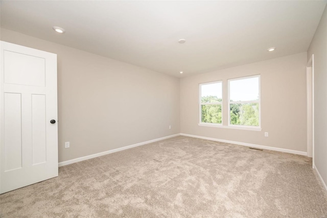 empty room featuring light carpet, visible vents, baseboards, and recessed lighting