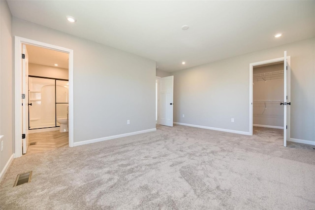 unfurnished bedroom featuring baseboards, visible vents, a walk in closet, and recessed lighting