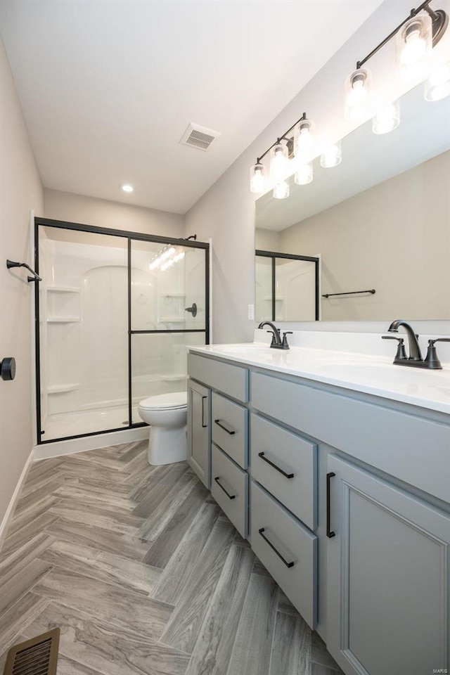 bathroom featuring double vanity, a shower stall, and visible vents