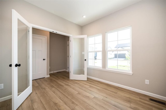 unfurnished bedroom featuring light wood-style floors, french doors, visible vents, and baseboards