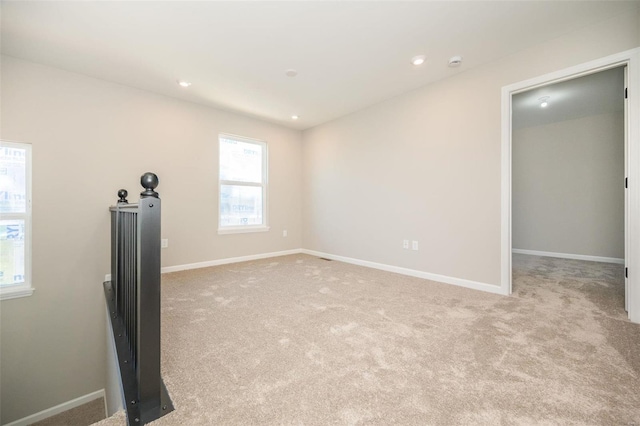 unfurnished living room featuring recessed lighting, light colored carpet, and baseboards