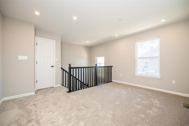 empty room featuring recessed lighting, light colored carpet, visible vents, and baseboards