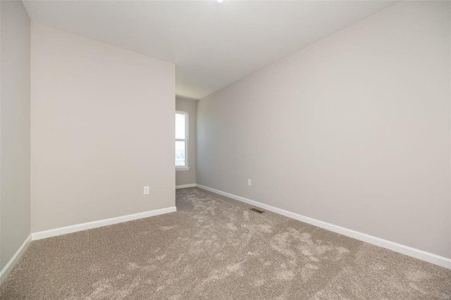 unfurnished room with light carpet, visible vents, and baseboards