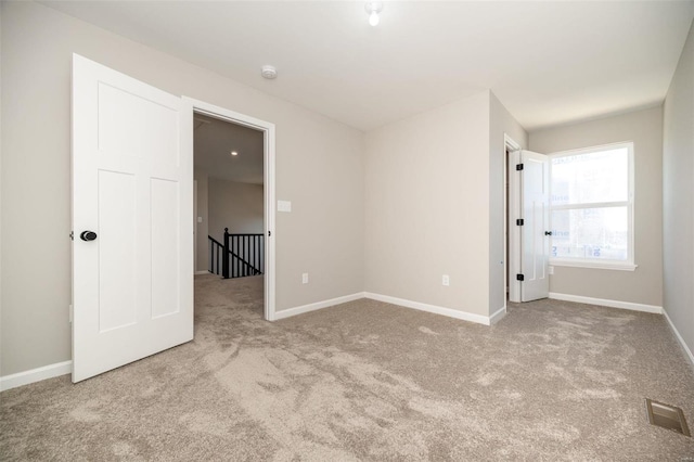 unfurnished bedroom with light carpet, visible vents, and baseboards