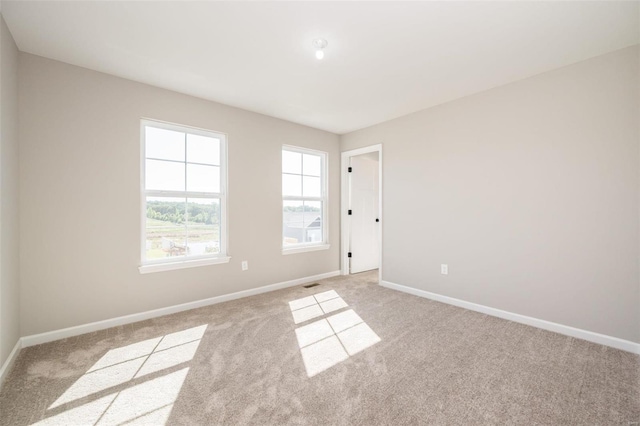 unfurnished room with visible vents, light colored carpet, and baseboards