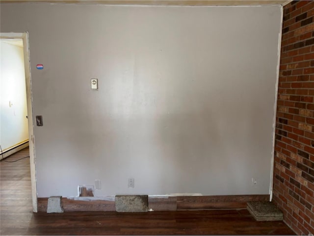 unfurnished room featuring a baseboard radiator and dark hardwood / wood-style floors