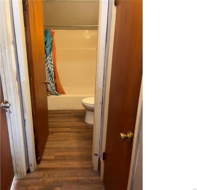 bathroom with curtained shower, wood-type flooring, and toilet