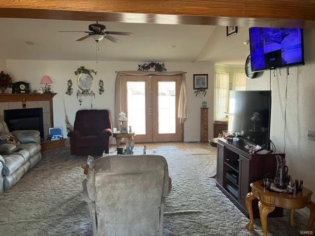 carpeted living room with french doors, lofted ceiling, a tiled fireplace, and ceiling fan