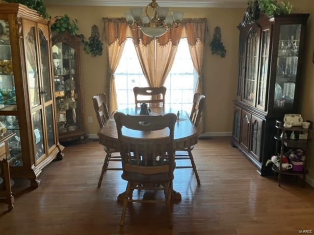 dining space featuring crown molding, an inviting chandelier, and dark wood-type flooring