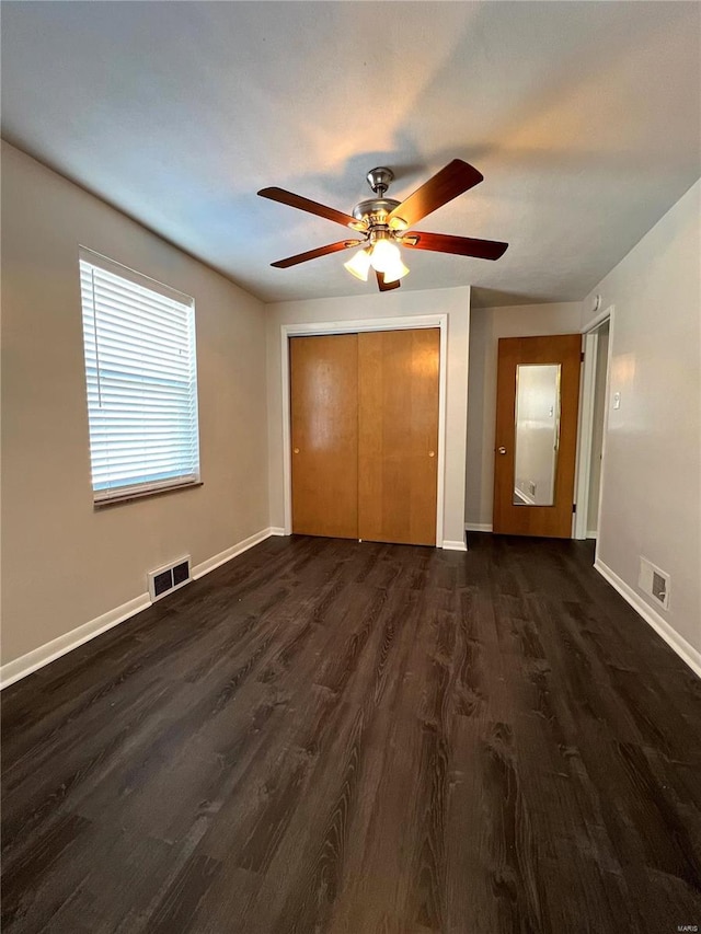 unfurnished bedroom with dark hardwood / wood-style flooring, ceiling fan, and a closet