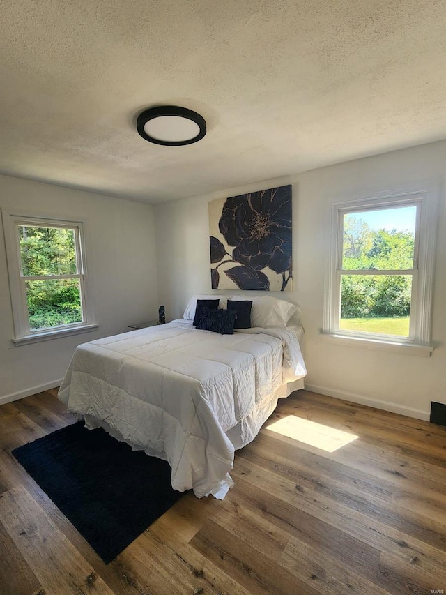 bedroom with hardwood / wood-style floors and a textured ceiling