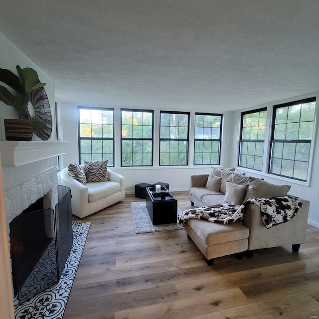 living room with a textured ceiling, a high end fireplace, and light hardwood / wood-style flooring