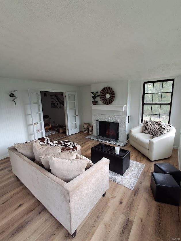 living room with a high end fireplace, a textured ceiling, and light hardwood / wood-style flooring