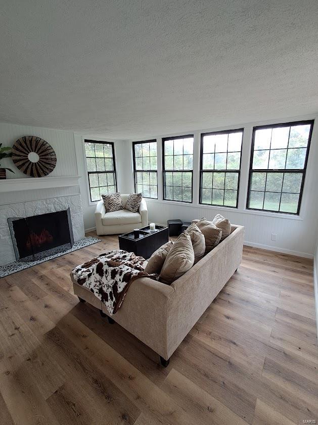 living room featuring a textured ceiling, light hardwood / wood-style floors, and a fireplace