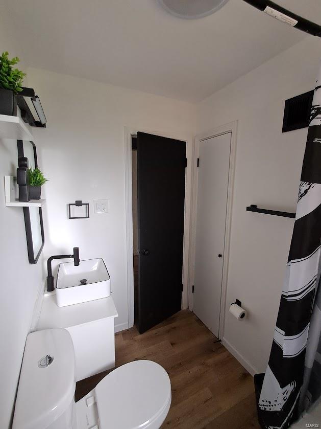 bathroom featuring wood-type flooring, toilet, and sink