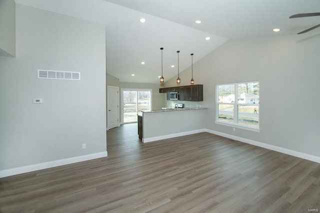 unfurnished living room with high vaulted ceiling, dark wood-type flooring, and plenty of natural light