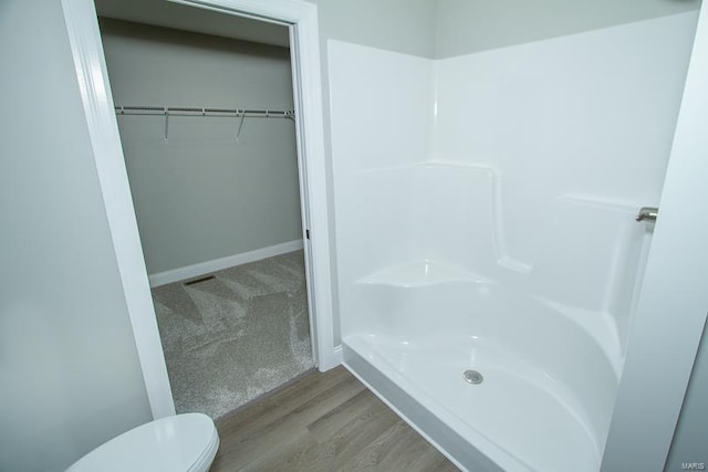 bathroom with a shower, hardwood / wood-style flooring, and toilet