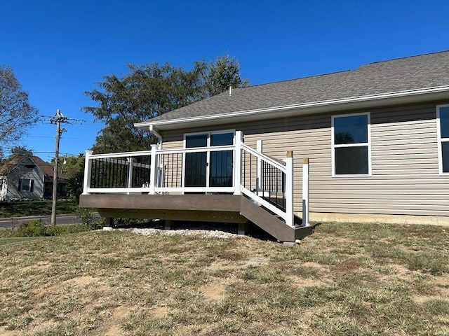 back of property featuring a deck and a lawn